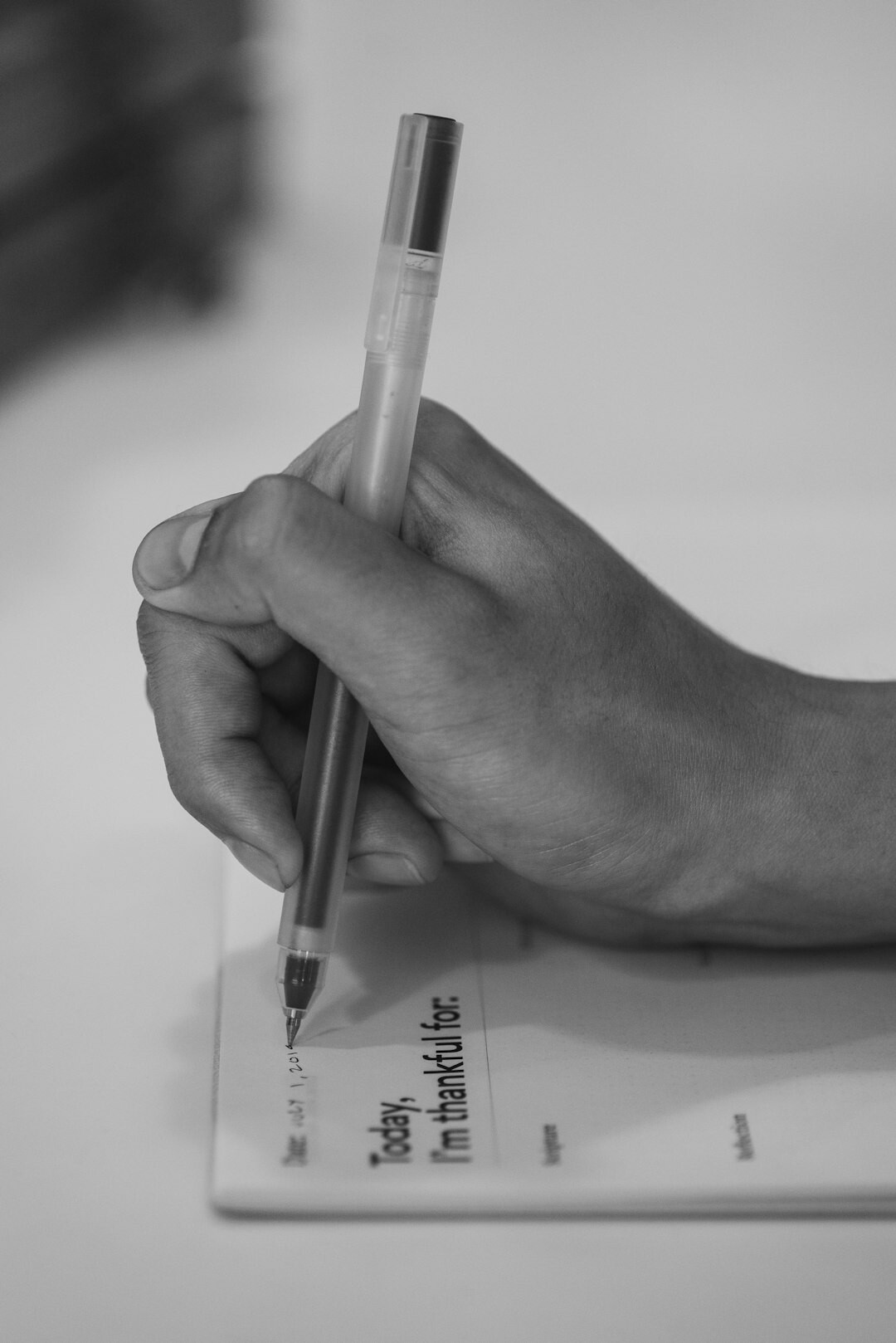 Close-up of hands writing on a document with a pen